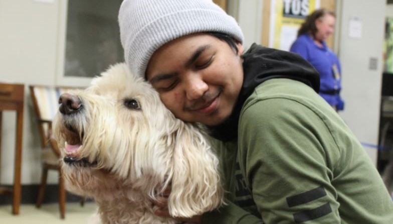 An Honors student hugs a white poodle