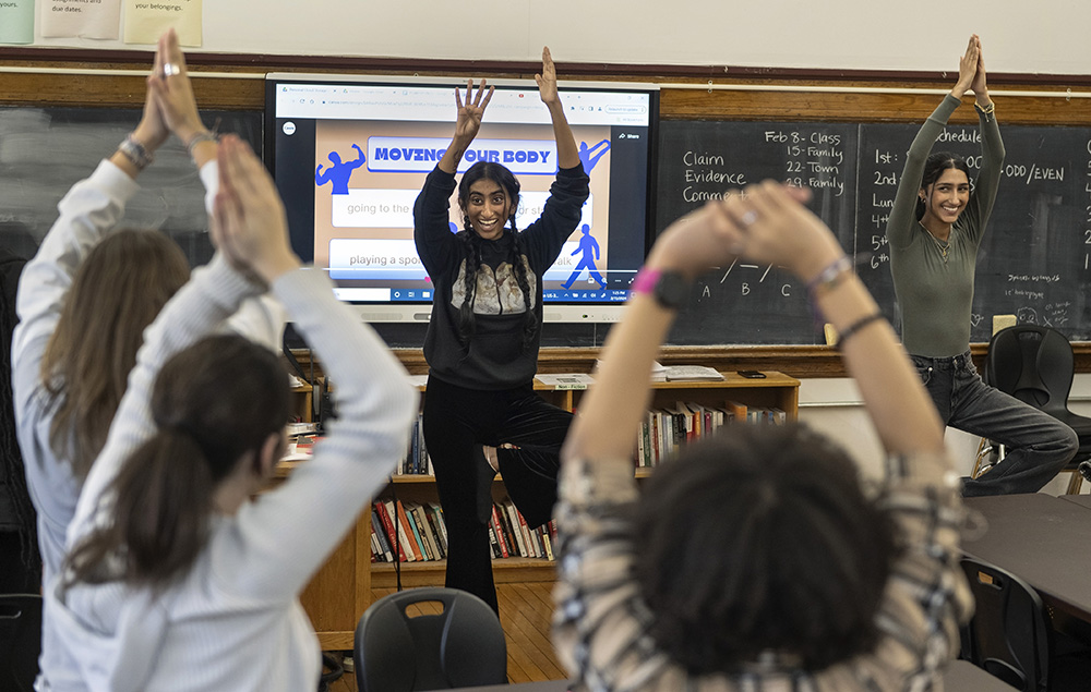 VCU Honors College students Arya Kalathil (left) and Simrah Ansari (right) lead students in the WHAM (Wellness, Happiness and Mindfulness) class at Open High School in some yoga moves.