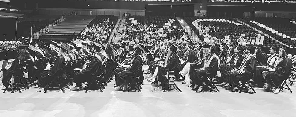 THe Honors COllege class of spring 2023 sits in ful regalia at the Siegel Center during their commencement ceremony