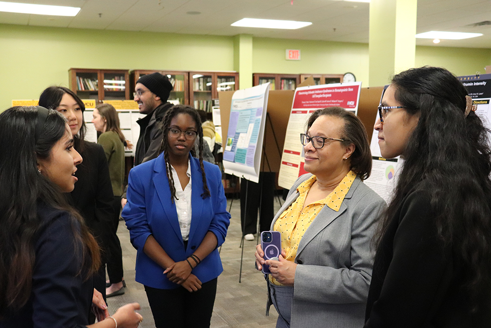 Honors students present a research poster to fellow students and an Honors administrator