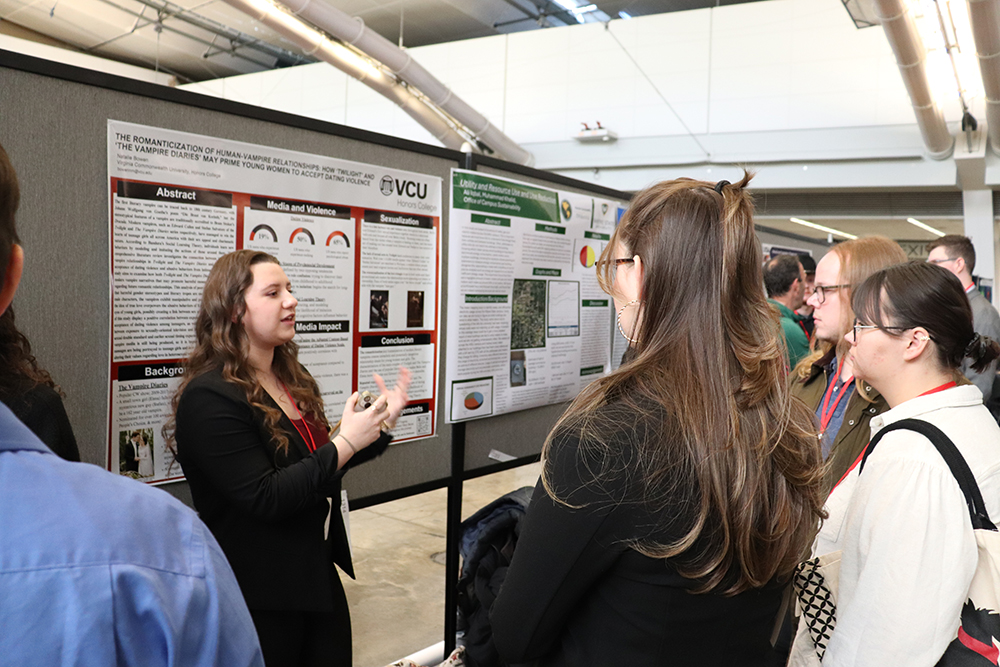 An Honors students presents to a group during a poster session at N C U R 2025