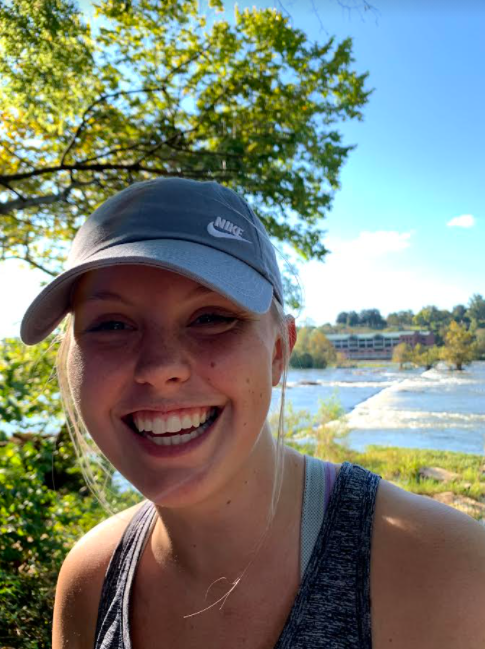 A student smiles toward a camera with the James River in the background