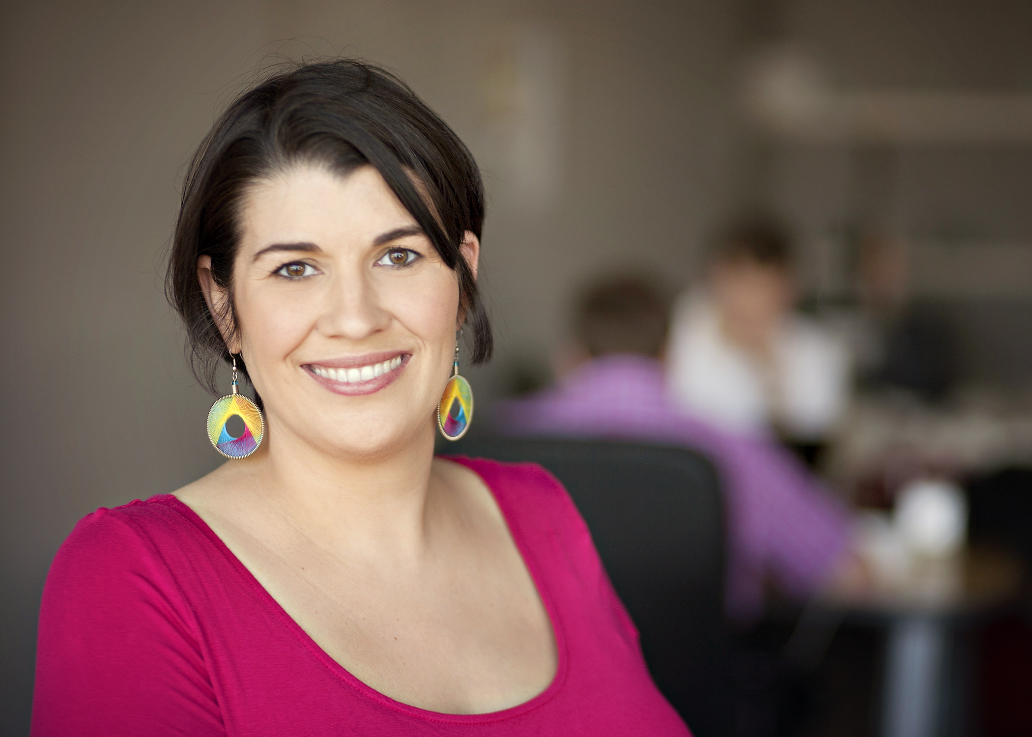 Andrea Goulet headshot where she is wearing a pink blouse with yellow and green circle earrings